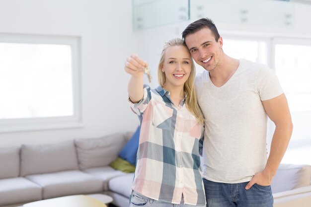 Happy smiling young couple hugging while showing a keys of their new house