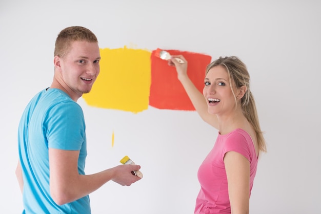 happy smiling young couple painting interior wall of new house