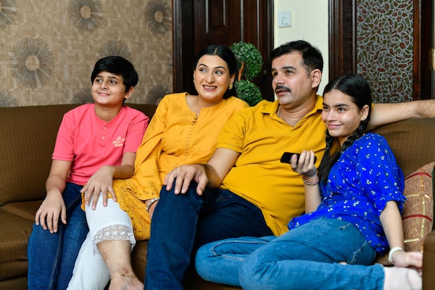 Happy smiling young family watching tv indian pakistani
model