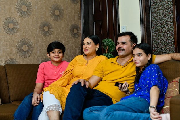 Foto giovane famiglia sorridente felice che guarda la tv modello pakistano indiano