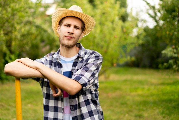 Foto giovane manodopera agricola bella sorridente felice con la barba con il protrait a degli strumenti di giardino