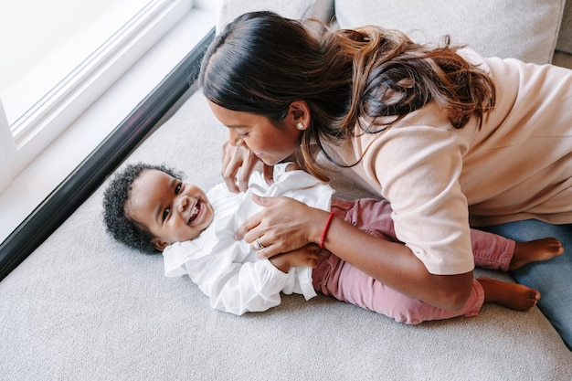 happy smiling young indian mother playing with black baby girl daughter family mixed race people