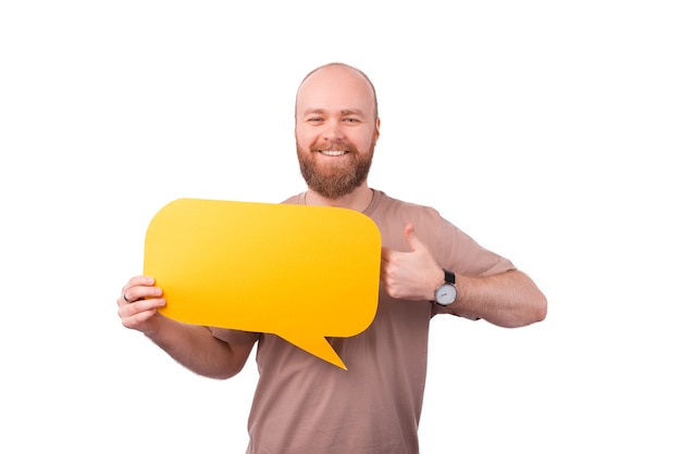 Happy smiling young man with beard holding empty speech bubble and showing thumb up