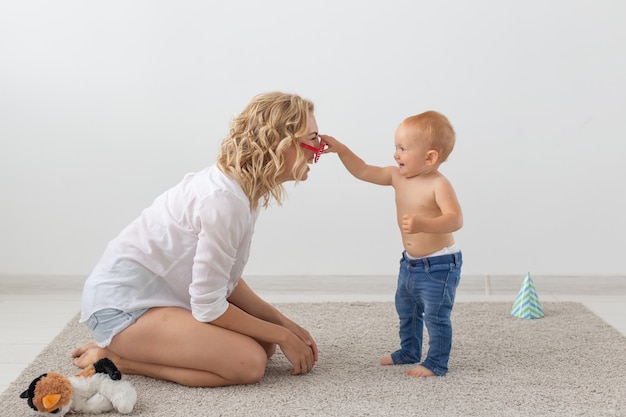 Happy smiling young mother playing with little baby at home