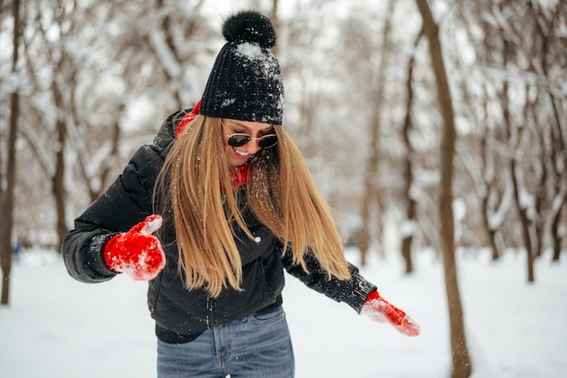 Happy smiling young woman having fun with snow in a winter park