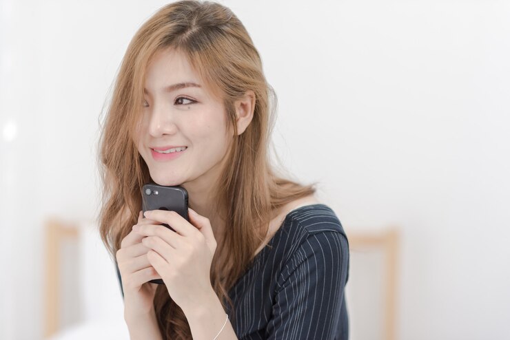 Photo 幸せな笑顔の若い女性は彼女の携帯電話を保持します