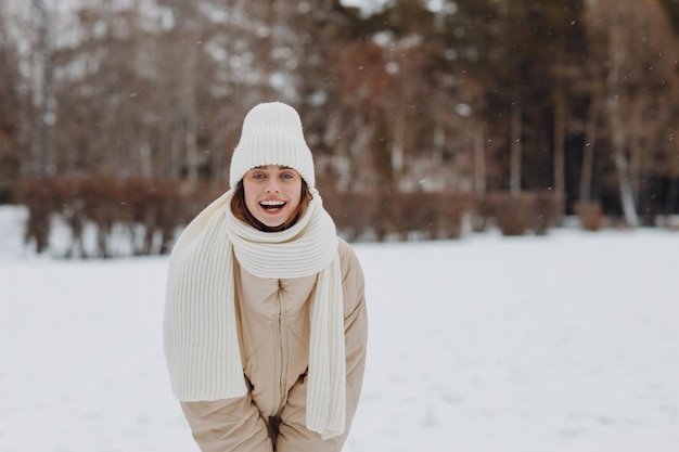 写真 雪の冬の公園で冬の天気を楽しんでいる幸せな笑顔の若い女性の肖像画着ているコートスカーフ帽子手袋