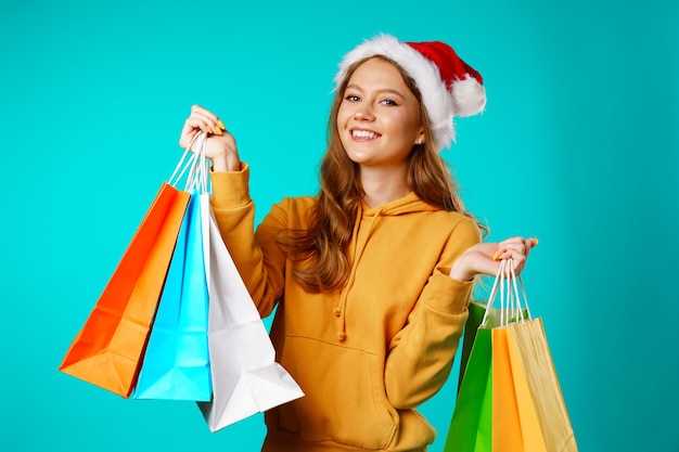 Happy smiling young woman in santa hat holding shopping bags