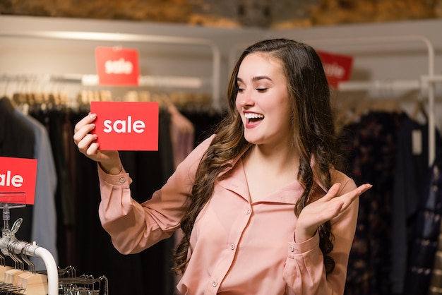 Happy smiling young woman with red sale sign