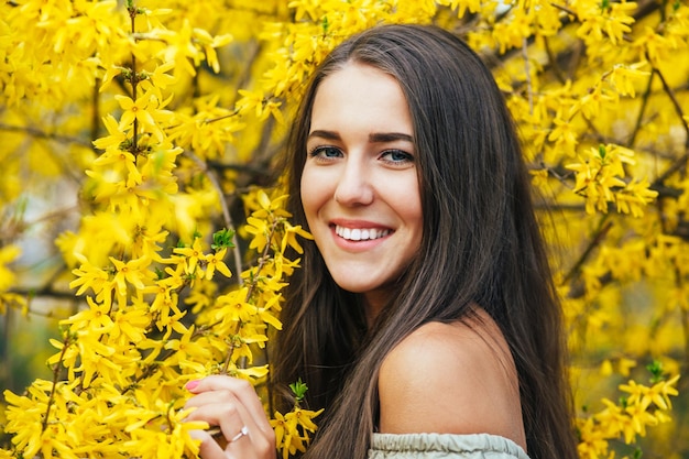 Happy smiling young woman with spring flowers at garden