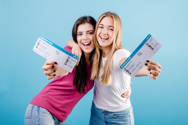 Happy smiling young women with plane tickets on blue