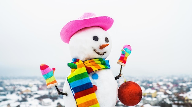 Happy snowman in hat colorful scarf and mittens with christmas toy snow man holds new year ball