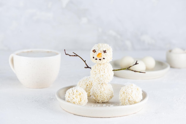 Happy snowman made of coconut vegan truffles with a cup of coffee Sugar gluten and lactose free