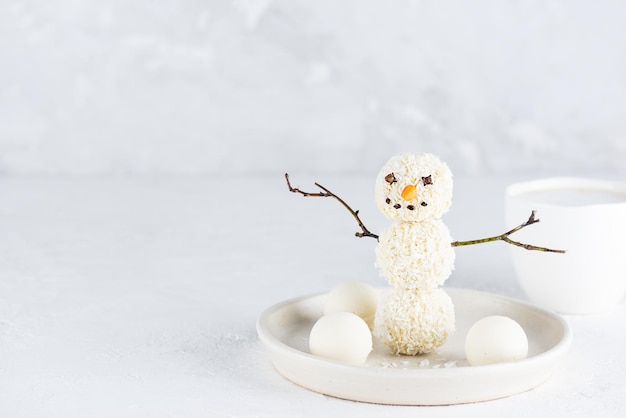 Happy snowman made from coconut vegan candies on a light background Sugar gluten and lactose free