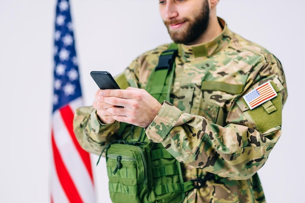 Happy soldier in a cap and with backpack smiling tapping on his