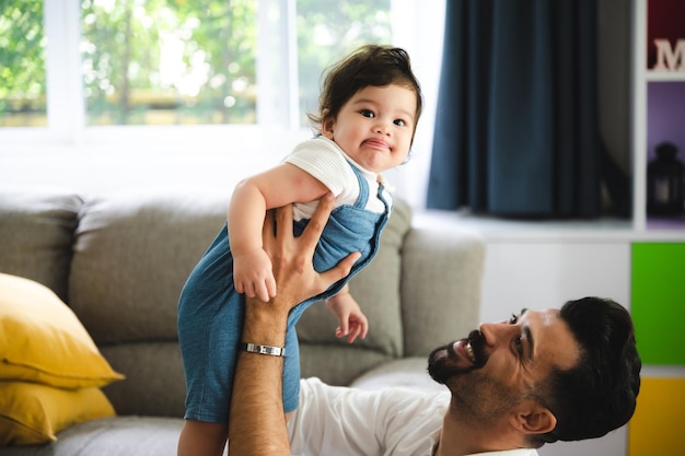 家族の父と母と一緒にサポートすることによって家で遊ぶ幸せな息子の子の赤ちゃん