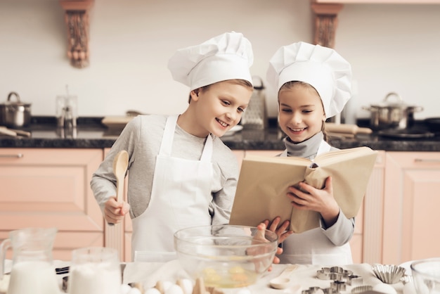 Figlio e figlia felici cucinano con il libro di ricette.