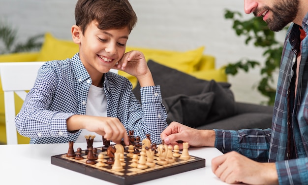 Foto figlio felice che gioca a scacchi con suo padre