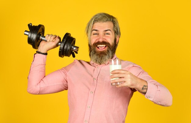 Happy sportsman hold barbell bearded man drink useful milk healthy diet after exercise in gym Fitness milk and weight loss The concept of beauty and health of the benefits of Drink