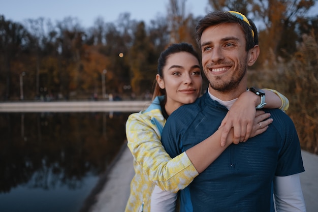 Happy sporty couple portrait outdoors while hugging