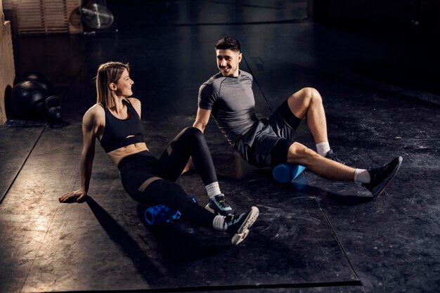 Happy sporty couple practicing with foam rollers at the gym