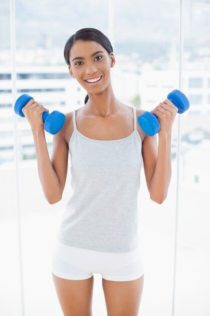 Happy sporty model exercising with dumbbells