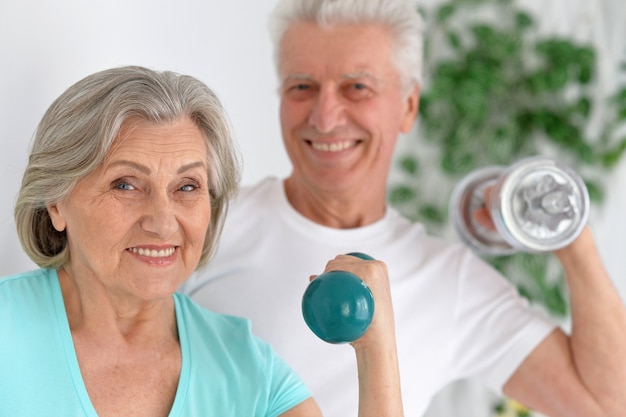 Happy sporty senior couple exercising with dumbbells