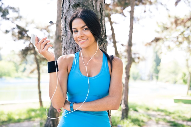 Счастливая спортивная женщина, держащая смартфон на открытом воздухе