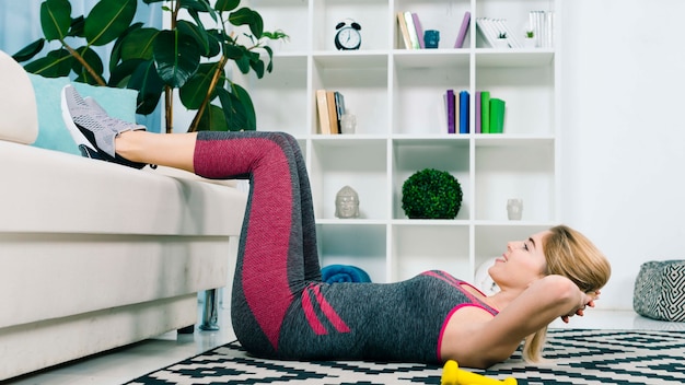 Photo happy sporty young woman doing fitness exercise in the living room