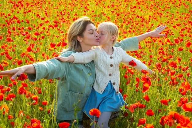 Happy spring family mother with daughter on the poppies meadow beautiful mom and daughter on a poppy
