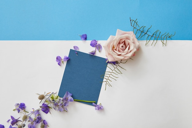 Happy spring lettering. Greeting blue card with blank space and flowers around. Top view, flat lay