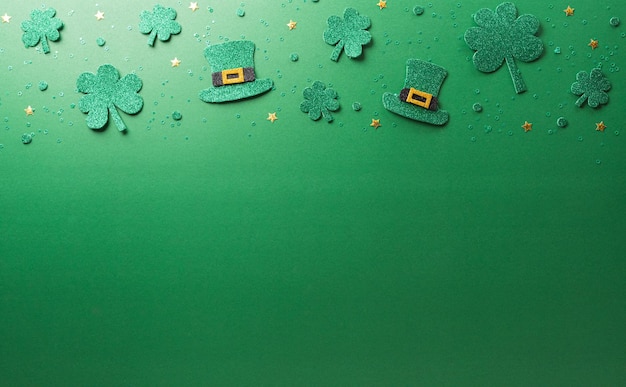 Happy St Patrick's Day decoration concept made from shamrocks clover leaf and leprechaun hat on green background