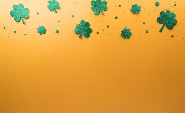 Happy St Patrick's Day decoration concept made from shamrocks clover leaf and leprechaun hat on yellow background