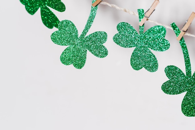 Happy St. Patricks Day background. Green glitter shamrocks homemade garland, copy space.