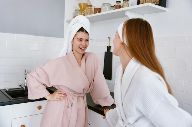 Happy student girls standing and chatting on home kitchen