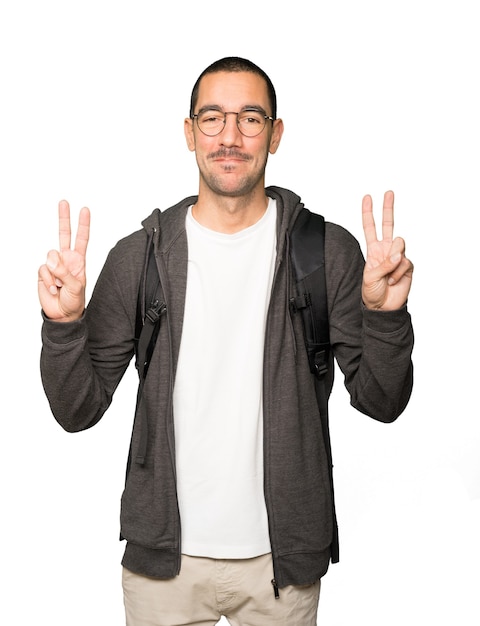 Happy student making a victory gesture with his fingers