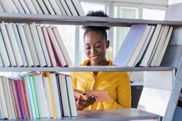 Happy student picking up books in library.