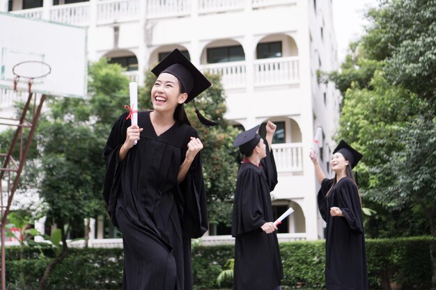 Photo happy student standing with diploma with friends behind celebrating success education goal concept