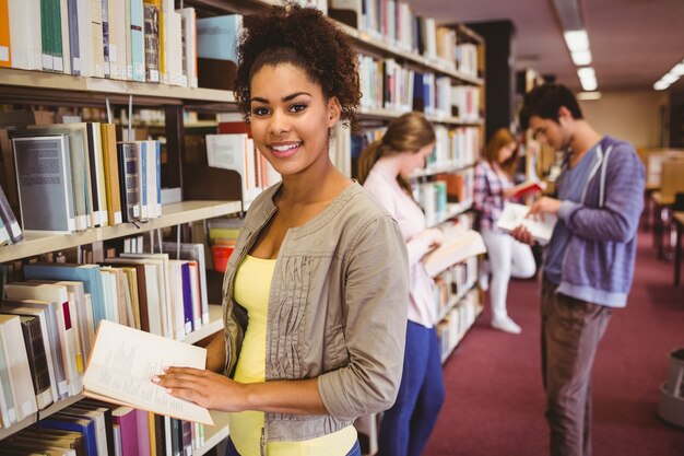 Happy student taking book from shelf