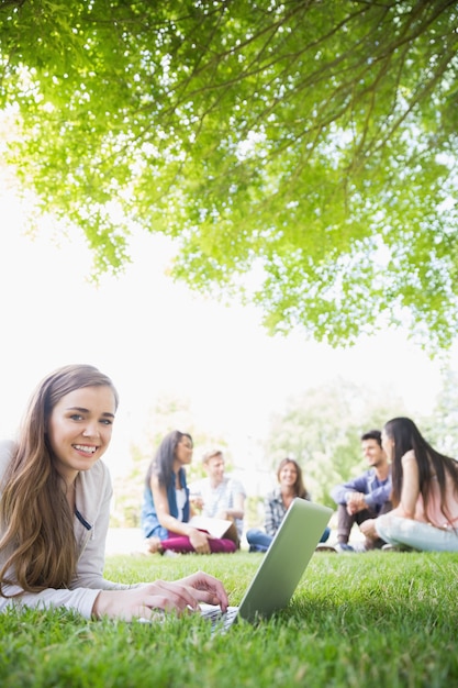 Happy student using her laptop outside