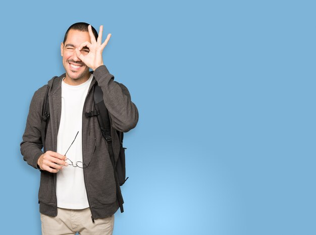 Happy student using his hands like a binoculars