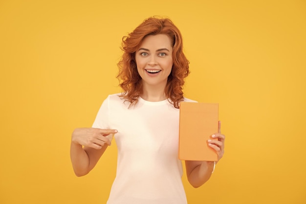 Happy student on yellow background girl study pointing finger on book