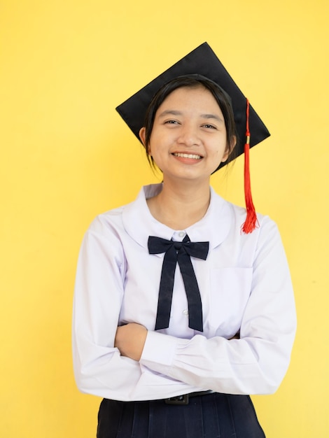 사진 행복한 학생 어린 소녀는 노란색 배경에 졸업 모자를 입습니다.
