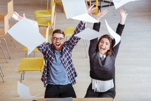 Photo happy students making mess in library by throwing papers