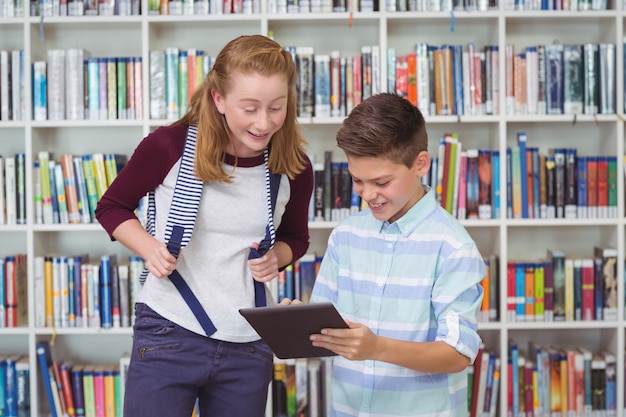 Happy students using digital tablet in library