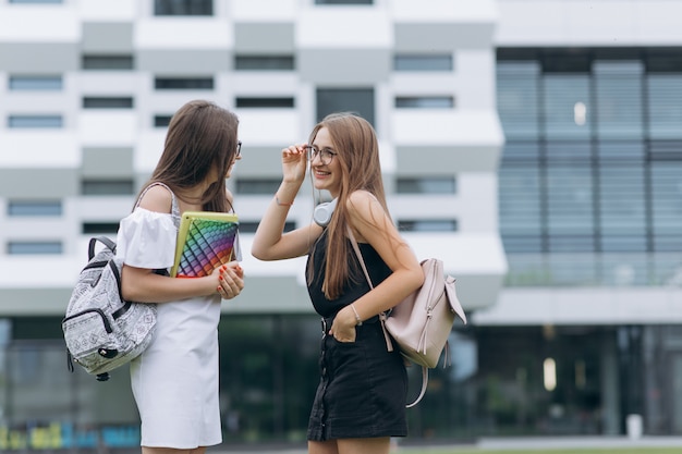 学校を歩いて幸せな学生。学生のグループは、近代的な建物の前を歩いて、楽しい話をします