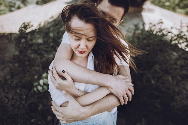 Photo happy stylish couple in love hugging on the beach in summer city modern woman and man in fashionable white clothes embracing romantic sensual moment hipster family on honeymoon