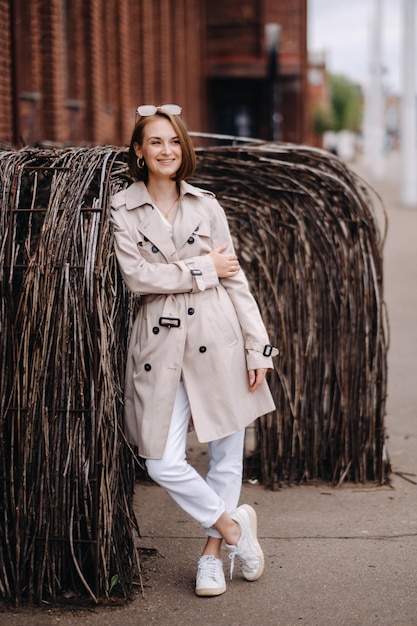 A happy stylish girl in a gray coat walks around the city