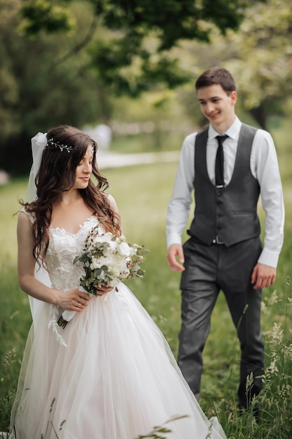 Happy stylish groom walking to the bride The bride is in the foreground Groom in a vest Portrait of the groom Spring wedding