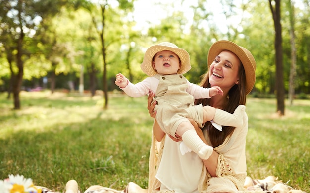 Felice famiglia elegante e amorevole. madre che gioca con il suo bambino all'aperto. bel bambino sorride e si diverte. concetto di festa della mamma.